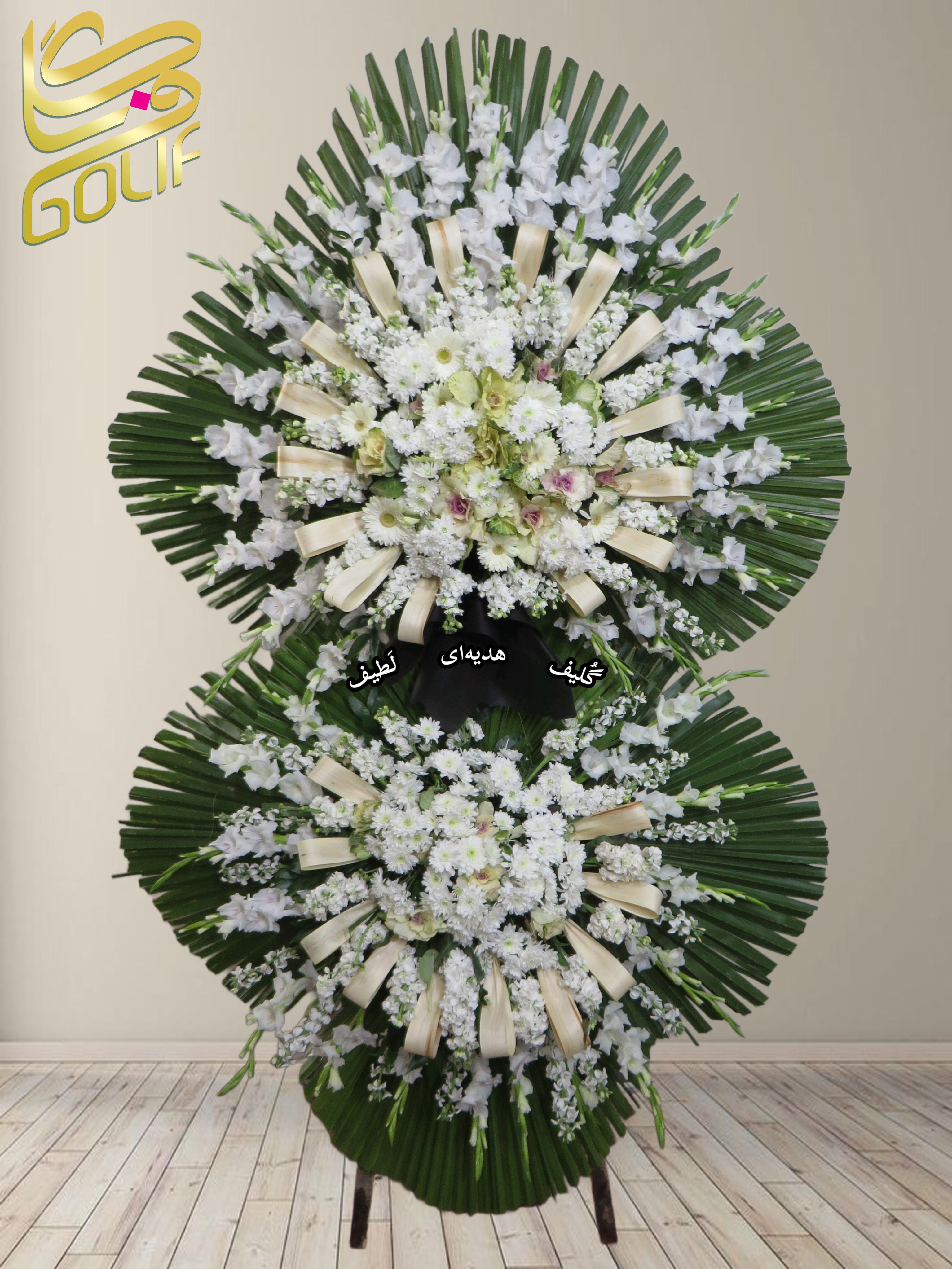 تاج گل تسلیت دو طبقه (گلایول, داوودی, ژربرا) تاج گل ختم، تاج گل ترحیم، تاج گل مراسم ترحیم گل‌هایی که در این تاج گل دیده می‌شوند شامل موارد زیر هستند: گلایول: گل‌های سفید بلند و جذاب که معمولاً برای مراسم تسلیت مناسب هستند. داوودی: گل‌هایی سفید که به طور گسترده‌ای در تاج گل‌های رسمی به کار می‌روند. ژربرا این گل‌ها در کنار برگ‌های سبز به صورت دایره‌ای طراحی شده‌اند.. سفارش آنلاین تاج گل سفارش آنلاین گل عکاسی شده توسط گل‌فروشی آنلاین گلیف